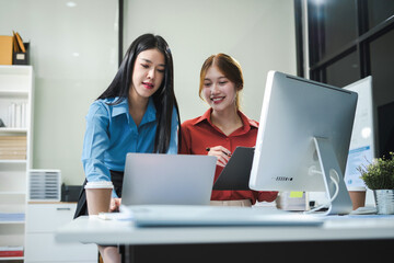 Businesswomen hand working with tablet and laptop computer with documents on office desk in modern office.