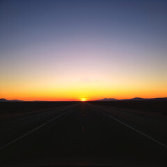 Fototapeta premium Open road at sunrise in a vast desert landscape