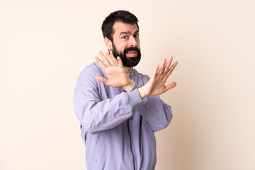 Caucasian man with beard wearing a jacket over isolated background nervous stretching hands to the front