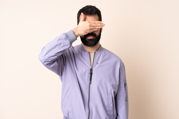 Caucasian man with beard wearing a jacket over isolated background covering eyes by hands. Do not want to see something