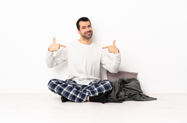 Caucasian man in pajamas sitting on the floor at indoors proud and self-satisfied