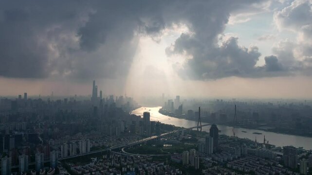 Drone view of Shanghai city in sunny cloudy rainy day at sunset, high angle view of ships sailing on Huangpu river and modern buildings with golden lights moving on sky, 4k time lapse footage.