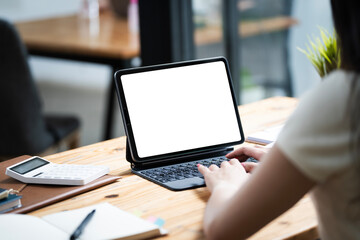 Woman typing on a laptop with a blank screen at a desk in a well-lit home office
