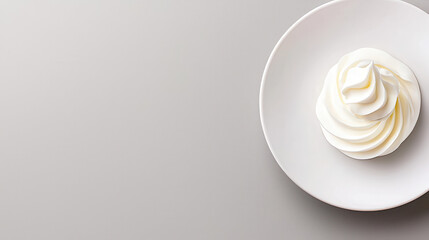 Whipped cream swirls artistically presented in a white bowl on a smooth grey background for culinary photography