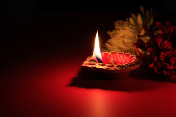 Diwali Hindu festival of lights celebration. Diya oil lamp on red background