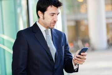 Businessman checking smartphone outside office