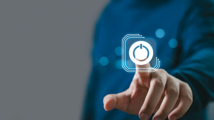 Person wearing blue shirt touching a digital power button icon on a transparent futuristic interface, representing technology and innovation.