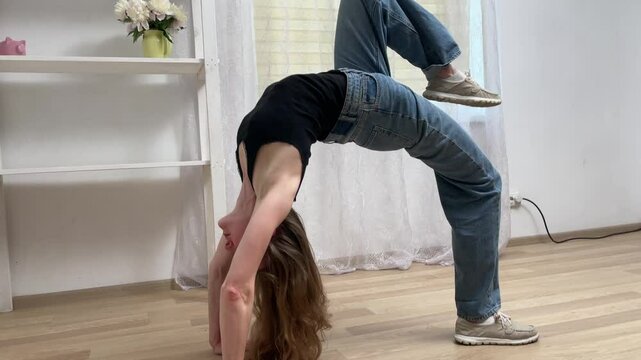 Woman practices a gymnastic routine at home, showcasing her skills in flexibility, strength, and balance
