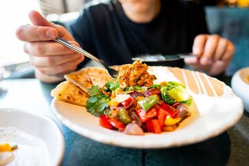 close-up of a person enjoying a vibrant, healthy meal with fresh vegetables and flatbread, perfect...