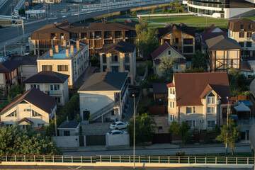Fototapeta premium Aerial view of residential houses in a modern suburban neighborhood with greenery and a highway in the background