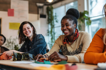 Fototapeta premium A group of young women are sitting around a table, smiling and laughing