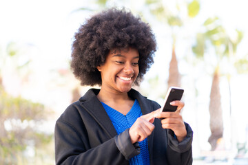 African American girl at outdoors sending a message or email with the mobile