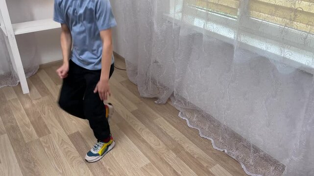 Young boy rehearses hip hop dance moves in a room, showcasing energy and creativity through rhythmic movements