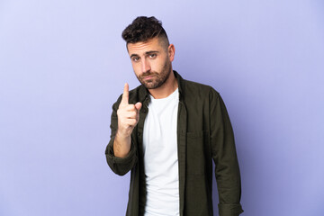 Caucasian man isolated on purple background frustrated and pointing to the front