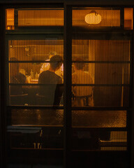 Customers  in Japanese Izakaya seen through screen