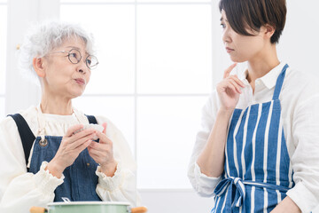 キッチンに立つ若い女性とシニア女性　料理イメージ