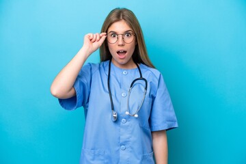 Young surgeon doctor woman isolated on blue background with glasses and surprised