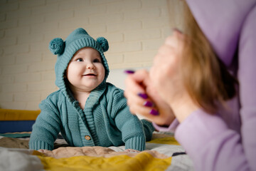 A young mother and her little daughter are playing and frolicking on the bed