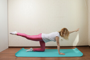 Woman doing yoga at home, practicing a tranquil lotus pose, embracing a fit and peaceful lifestyle.