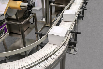 Industrial packing and labelling machine. High view of white cardboard boxes on the production...