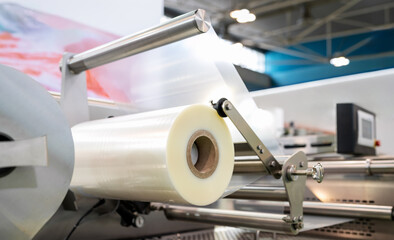 Close-up of Industrial plastic film roll in packaging machinery. Polyethylene film roll.