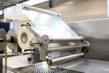 Close-up of Industrial plastic film roll in packaging machinery. Polyethylene film.