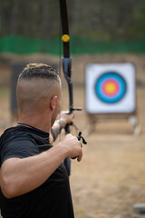 A man is practicing archery in a field