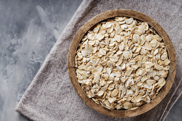 Wooden Bowl with Raw Oat Flakes on Linen Napkin, Vegan Food Concept, Top View, Copy Space