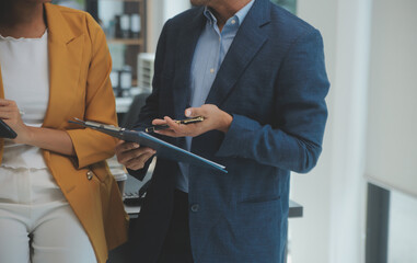 Entrepreneur Asian businessman and businesswoman discussing new business project in tablet in modern Meeting In Modern Office, Asian business casual concept.