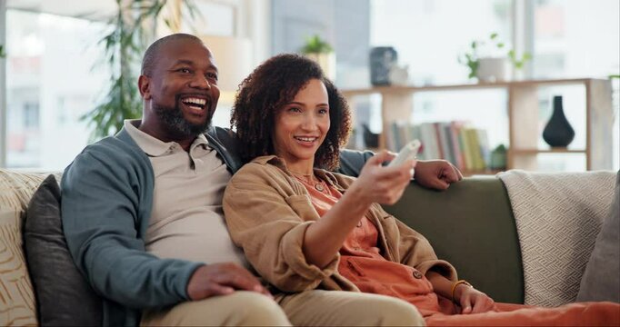Mature couple, watching tv and remote on sofa with smile, choice and click to change channel for movie. Man, woman and interracial love in home, relax and happy with search, streaming or subscription