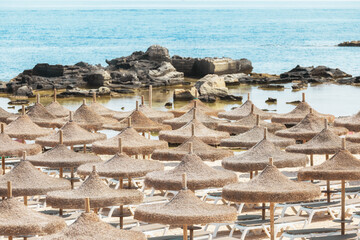 Straw umbrellas on the beach and turquoise water on a sunny day.