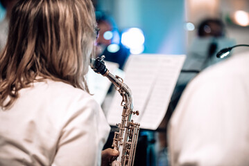 Alto saxophone player from behind during a brass band concert in atmospheric blue light