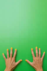 Woman showing all ten fingers with yellow painted nails on a green background
