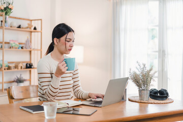 Asian businesswoman working on laptop at home office.