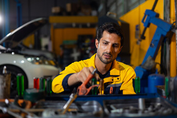 Auto mechanic selecting tools and spanner for repairs in auto repair shop. Hispanic latin male...