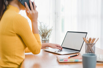 Woman using laptop with blank screen at home office.