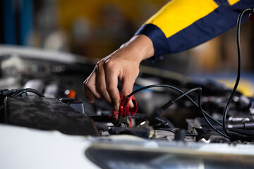 Battery inspection. Battery Capacity Tester Voltmeter. Closeup hand man professional mechanic repairs car working in garage. Car maintenance and auto service garage concept