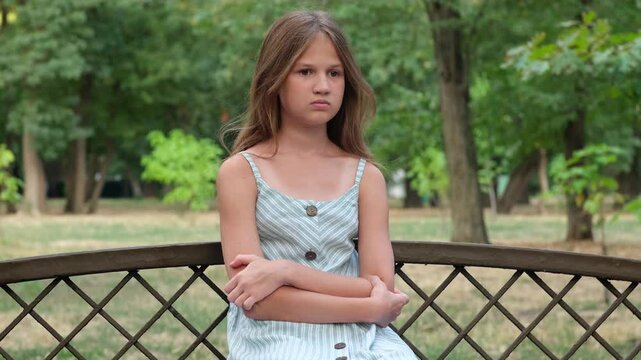 Frightened, upset girl sitting on a park bench. Depression, loneliness and problems concept