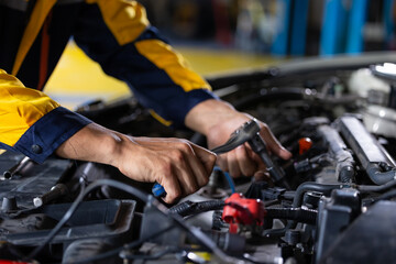 Close up mechanical hand with tools and spanner. Hispanic latin male mechanic repairs car in garage. Car maintenance and auto service garage concept