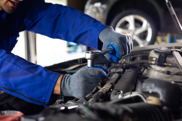 Close up mechanical hand with tools and spanner. Hispanic latin male mechanic repairs car in garage. Car maintenance and auto service garage concept