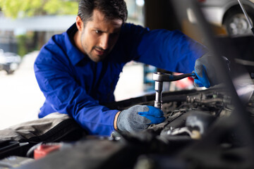 Close up mechanical hand with tools and spanner. Hispanic latin male mechanic repairs car in garage. Car maintenance and auto service garage concept