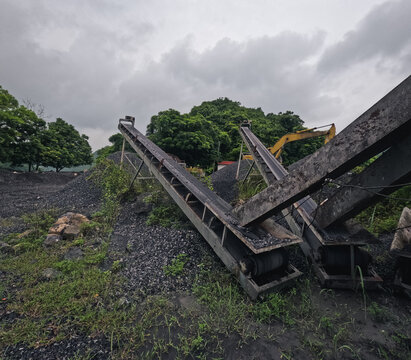 Wide angle shot of conveyor beld in a Vietnamese mine in Cat Ba Island during rainy season. The mine appears to be innactive at the moment and has collected some rust