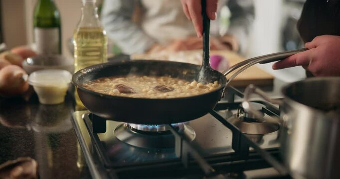 Cooking, stirring and hands of person in kitchen for recipe, culinary skills and pan on stove. Chef, mushroom and rice in dish for preparation, risotto process and private class in home for cuisine