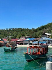 Obraz premium Asian boats at beautiful beach in Cambodia, island Koh Rong, red boat blue sea, white beaches and beach houses