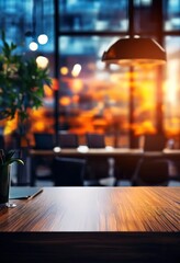 A wooden table with a plant and a glass of water on it, set against a blurred background of a restaurant interior with a hanging lamp and a window with a warm, orange glow.
