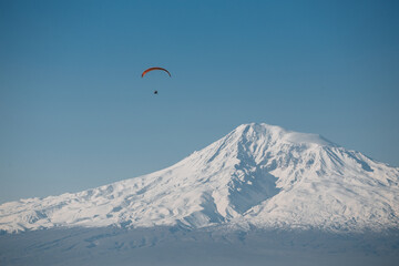 paraglider in the mountains at dawn against the backdrop of snowy mountains Ararat
