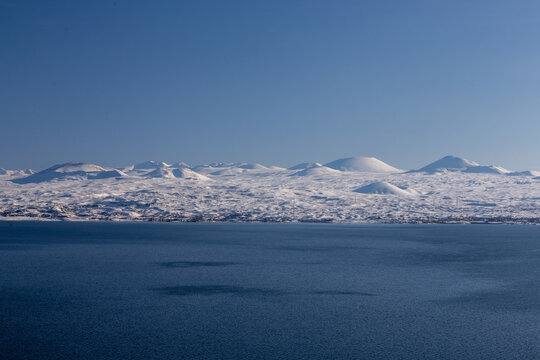 snow capped mountains on lake sevan in clear weather at sunset