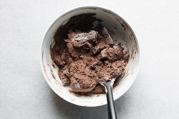 Overhead view of chocolate cookie dough in a white ceramic bowl, top view of dark chocolate sugar cookie dough in a white mixing bowl, process of making chocolate sugar cookies