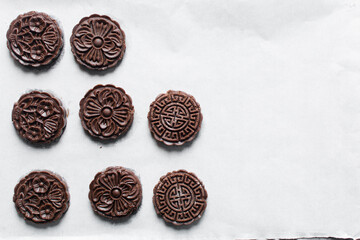 Overhead view of stamped chocolate cookies on a parchment lined baking tray, top view of embossed chocolate sugar cookies on a white background