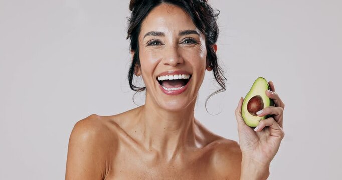 Woman, face and skincare with avocado in studio for natural treatment, facial wellness and organic transformation. Smile, female person and fruit for dermatology, nutrition glow and white background